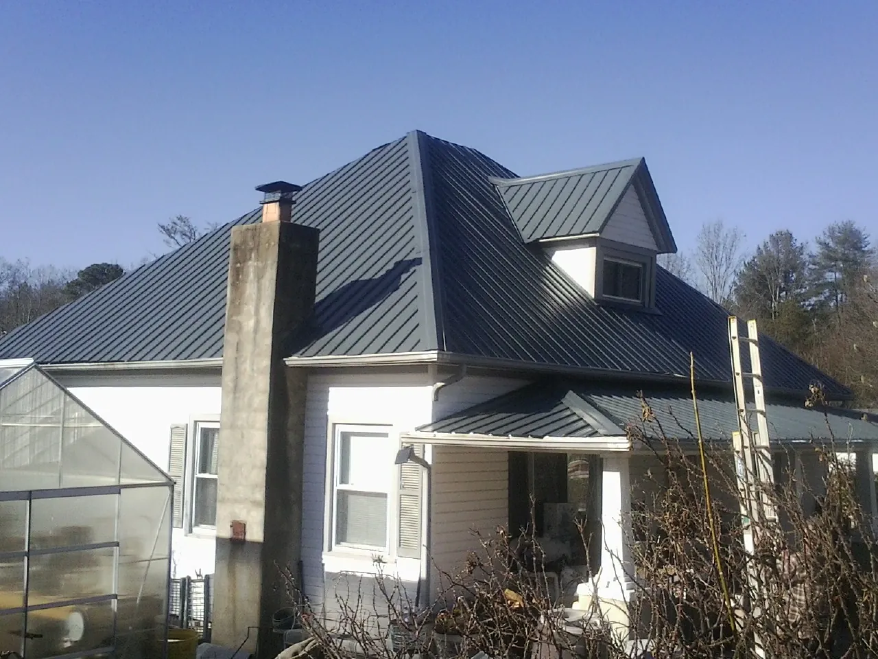 Dark blue standing seam metal roof on a white farmhouse with dormer — Slate & Tile Roof Repair by Roofing Brothers in Morton