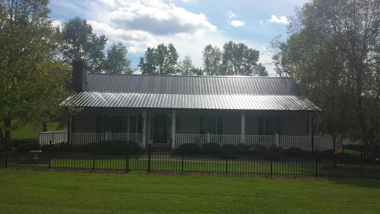 Gray metal roof on a brick ranch with a full width front porch — Gutter Guard Installation work by our crew in Morton